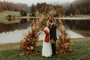 arche de mariage laïque devant le lac, décoration automnale, premier baiser